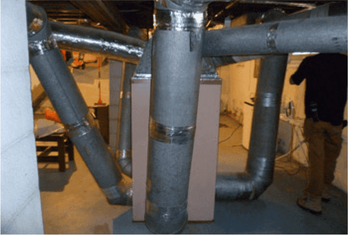 An Orzech's HVAC technician next to the ductwork system before replacement