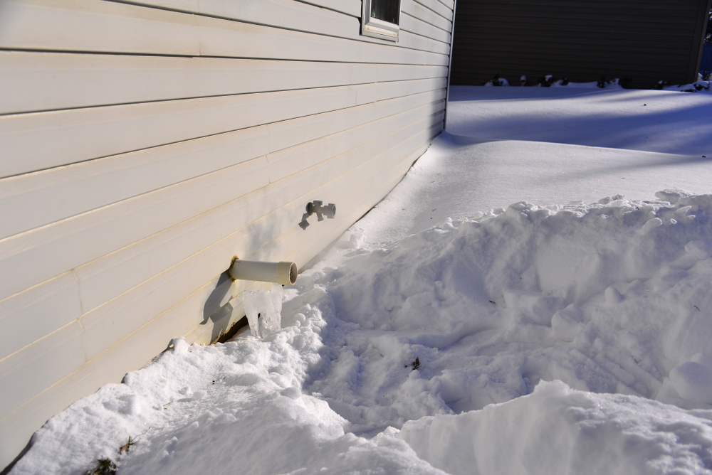 a frozen furnace exhaust outside a house.