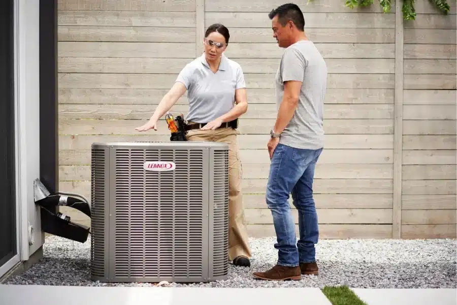 An HVAC specialist introducing an outdoor AC unit to a homeowner.